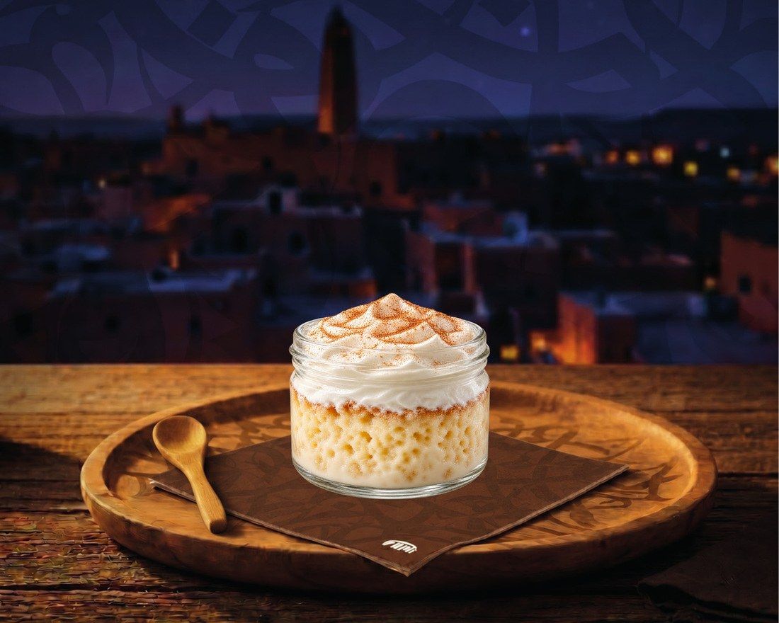 Un dessert en pot surmonté de chantilly et de cannelle, sur une serviette FAMI et un plateau en bois