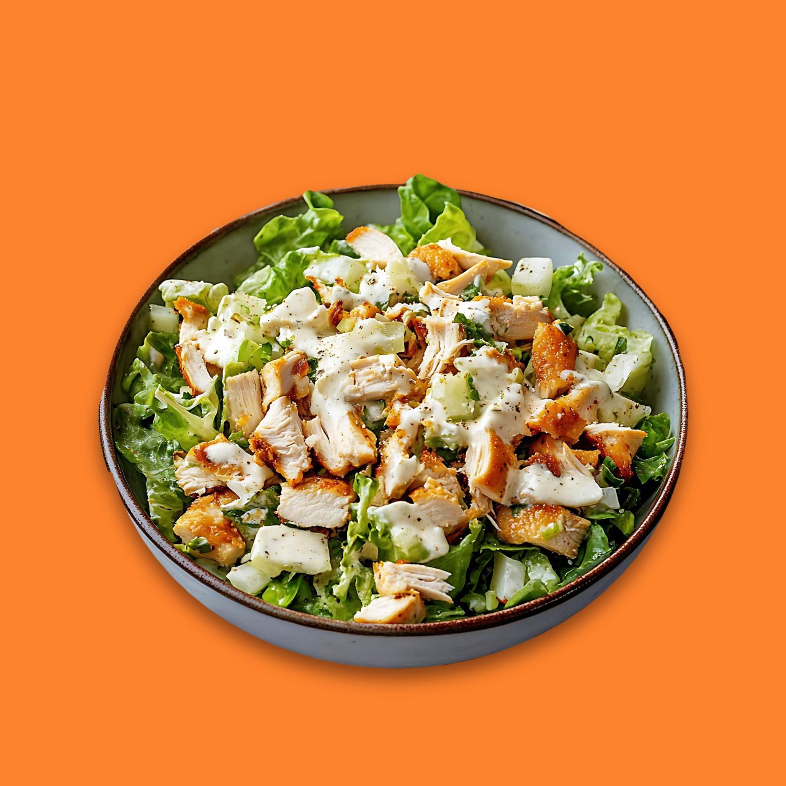 Une salade César : laitue, morceaux de poulet pané et sauce César, dans un bol en grès
